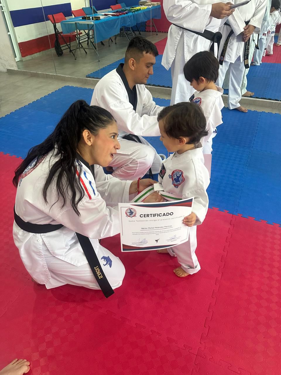 Instructora de Taekwondo entregando certificado a alumno en clases para niños Monterrey